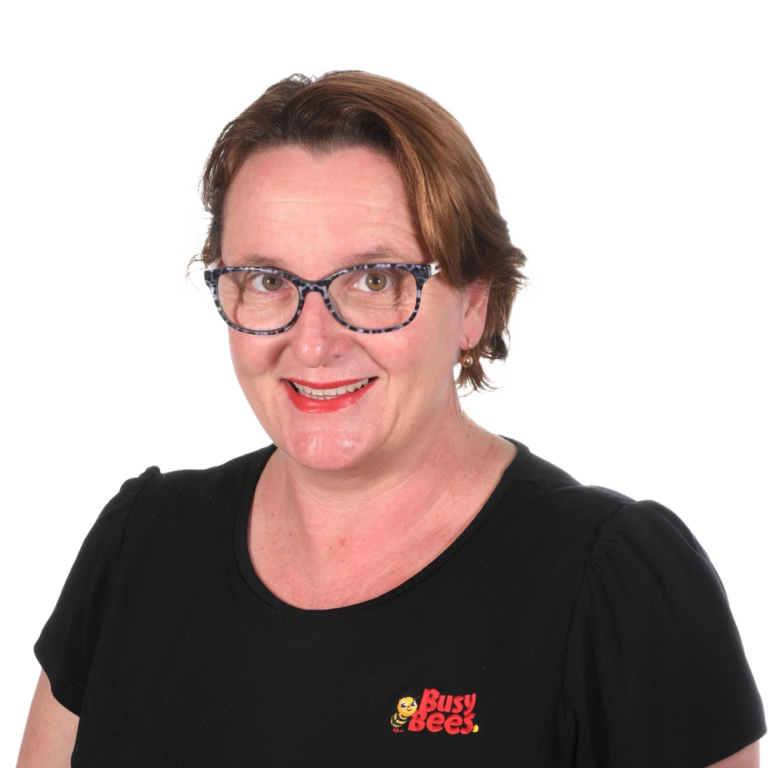 Tess Barry the Manager of Busy Bees Burpengary East, wearing glasses and a black shirt with a "Busy Bees" logo, smiling at the camera.