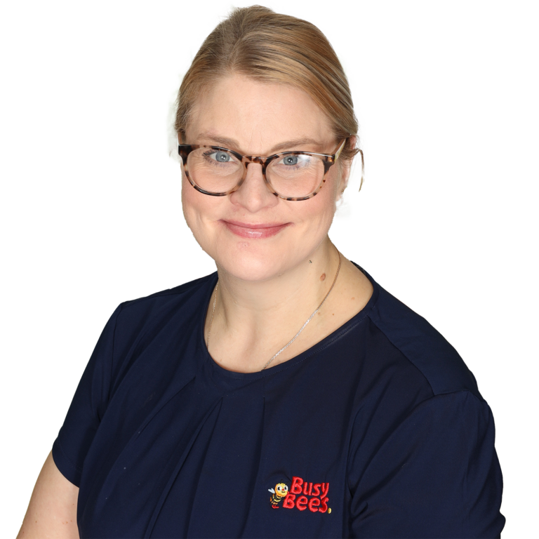 Emma Clark, Assistant Manager of Busy Bees on Hannan Street in Kalgoorlie wearing glasses and a navy blue shirt with a "Busy Bees" logo on the chest smiles at the camera.