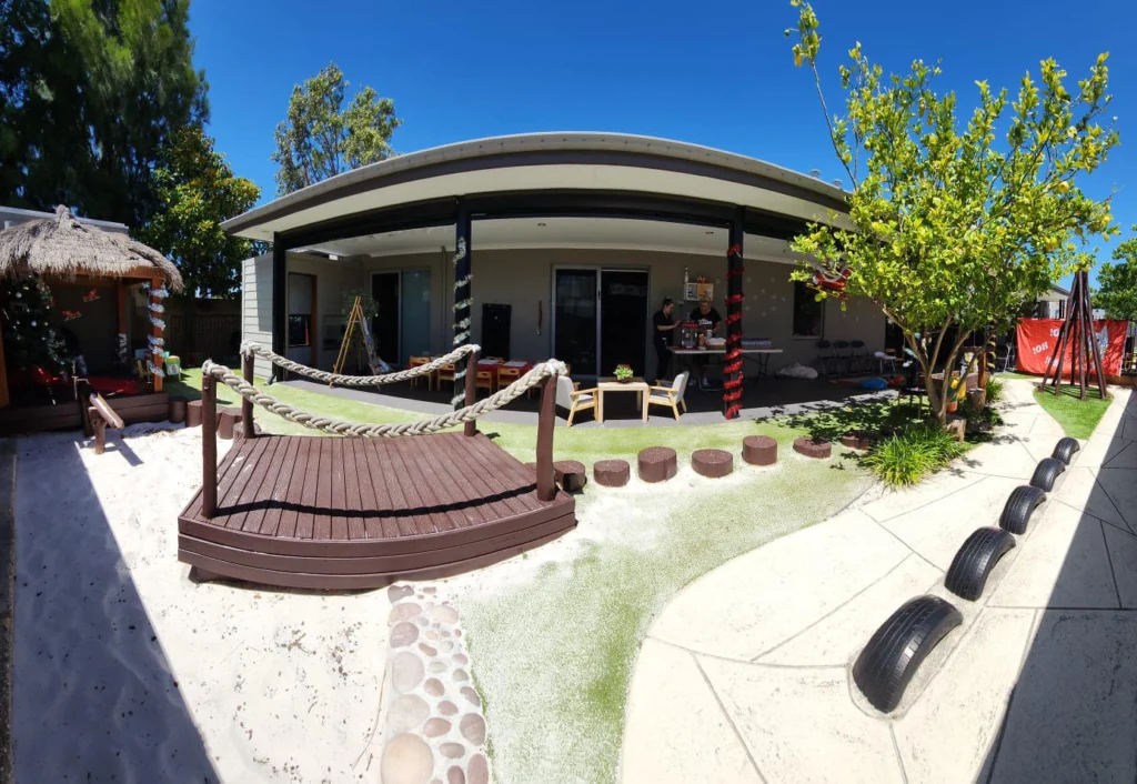 Outdoor playground a Byford Central child care featuring log stepping stones, a bridge, a bike track and a sandpit