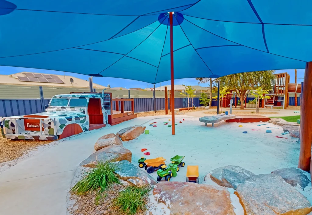 Shaded outdoor playground with sandpit.