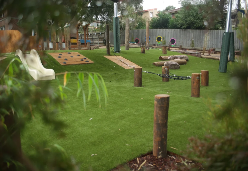 Spacious outdoor playground featuring timber logs, a slide and rock climbing.