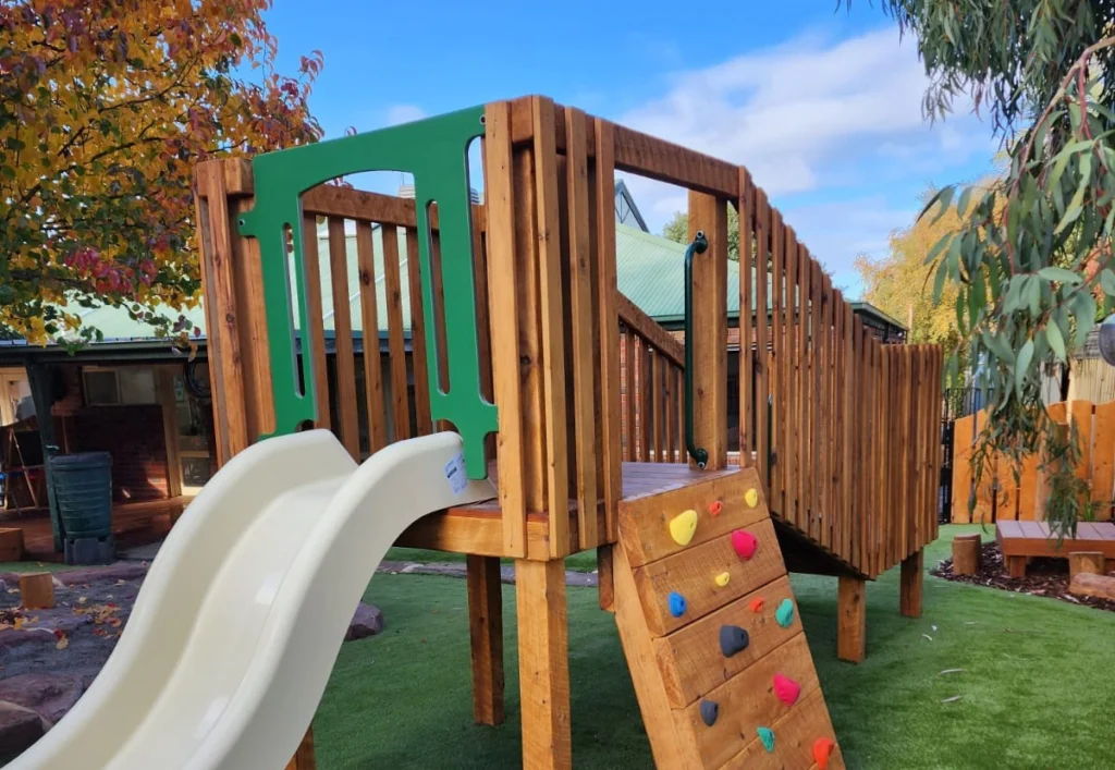 A timber fort with a slide and rock climbing at a daycare in Epping.