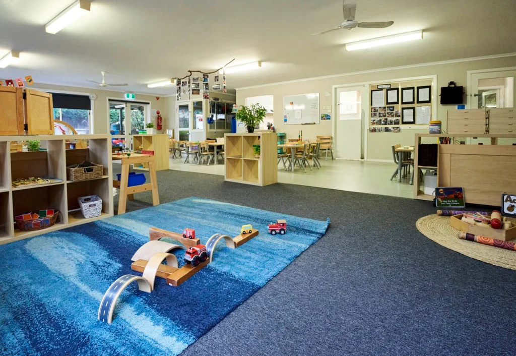 A childcare playroom with toy cars on vibrant blue mat, inviting creativity and play.