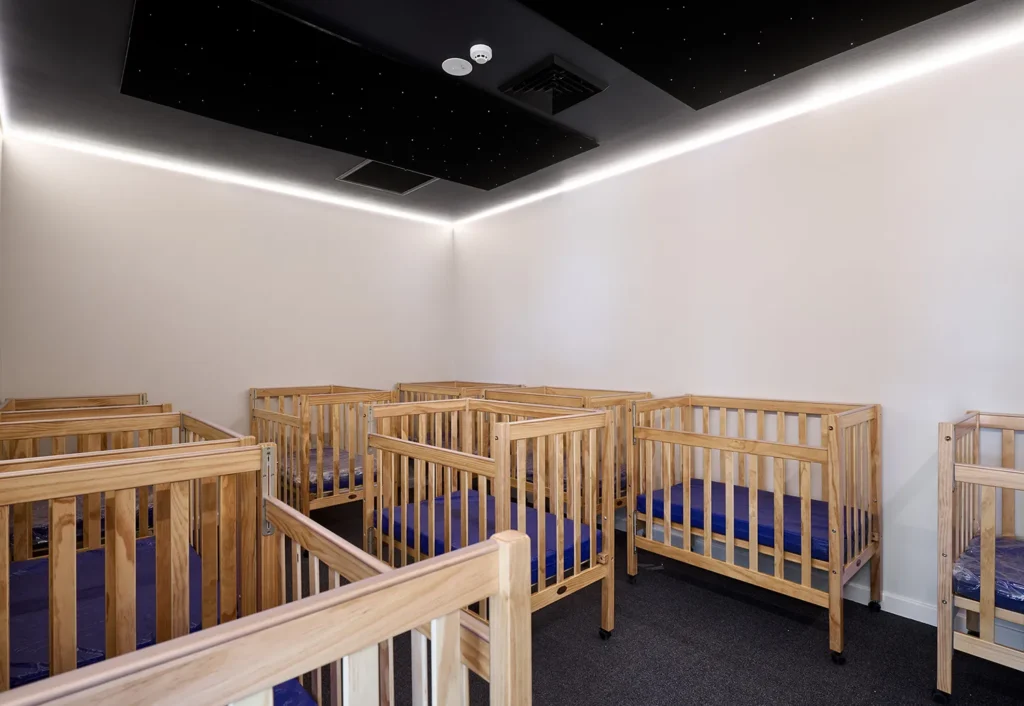 Cots in childcare sleeping room with starry night twinkle nights on ceiling