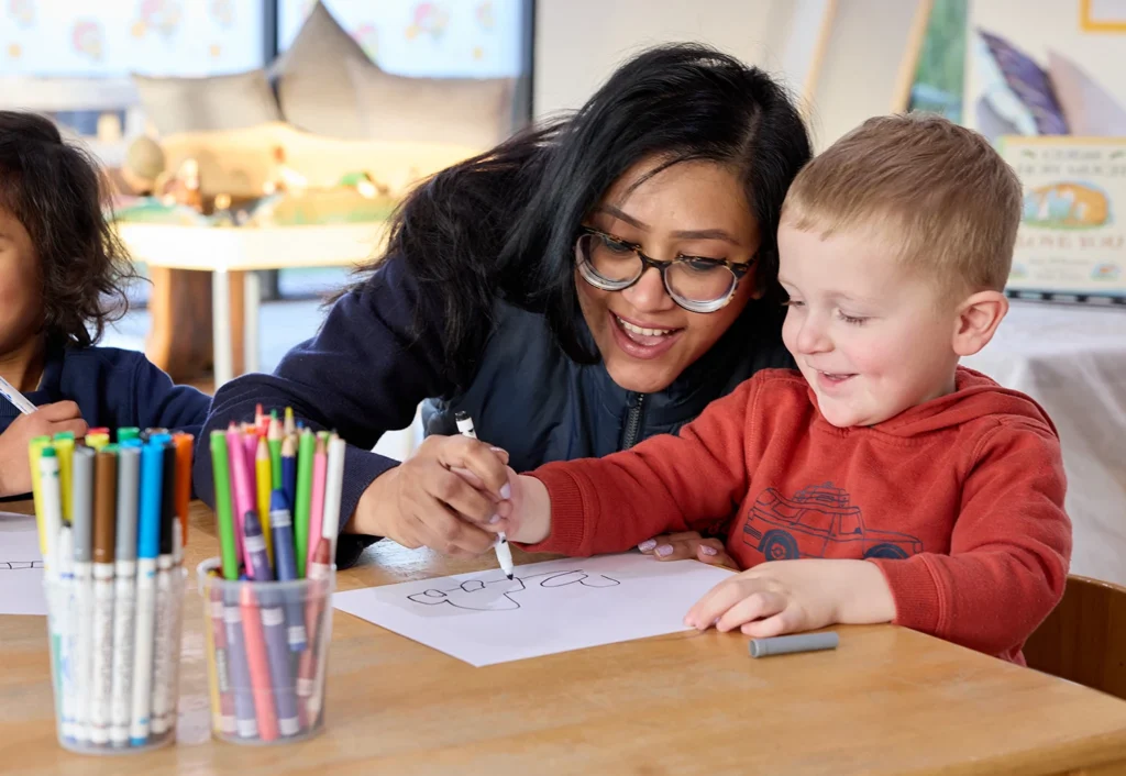 An Early Childhood Educator assisting a child to do art at Geelong Kindergarten.