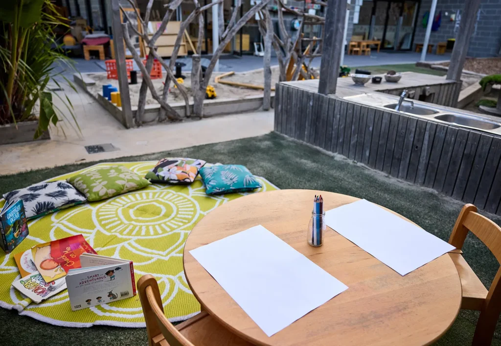 Drawing table and soft cushion reading area set in outdoor area at Geelong childcare.