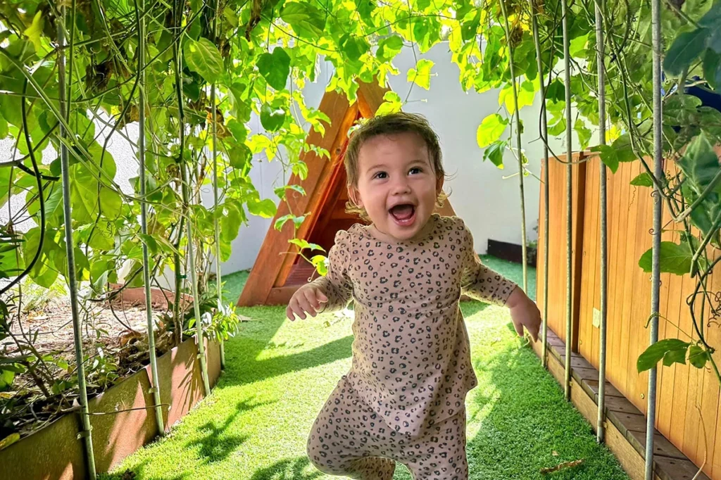 Young child running underneath a greenery rich garden arbour at a Everton Hills daycare