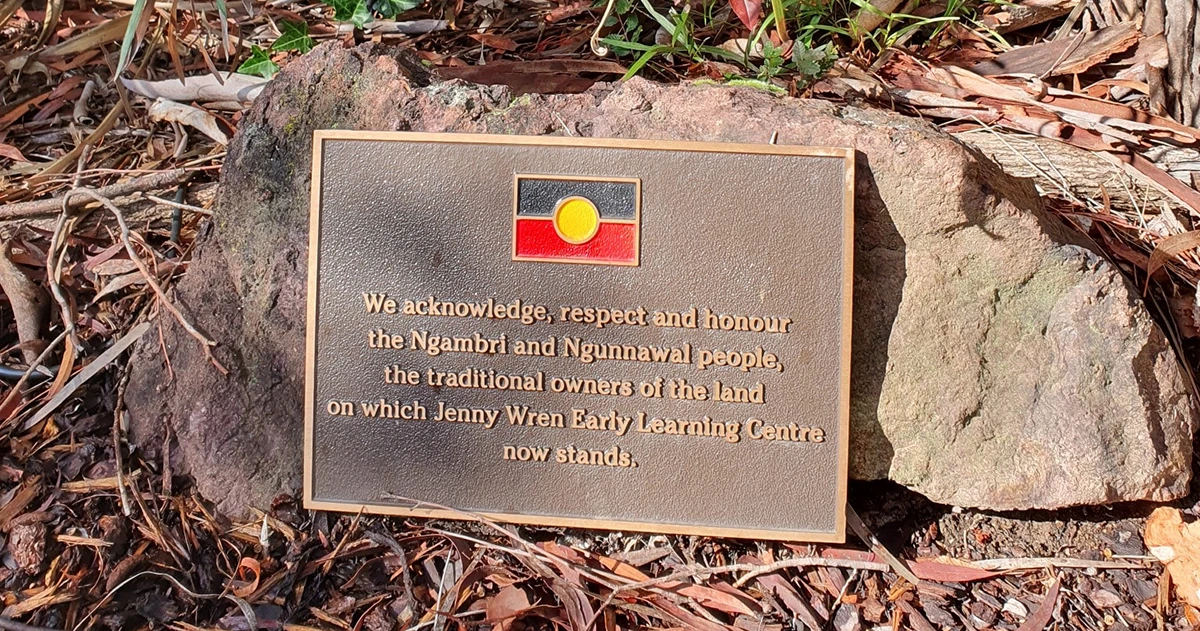 A plaque mounted on a stone acknowledges the Ngambri and Ngunnawal people as the traditional landowners of the Jenny Wren Early Learning Centre site. The plaque also features an abstract Indigenous design.