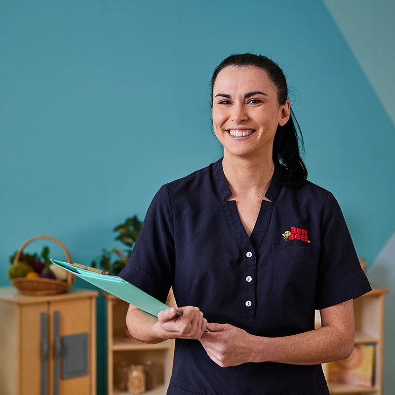 Early childhood teacher holding books and smiling