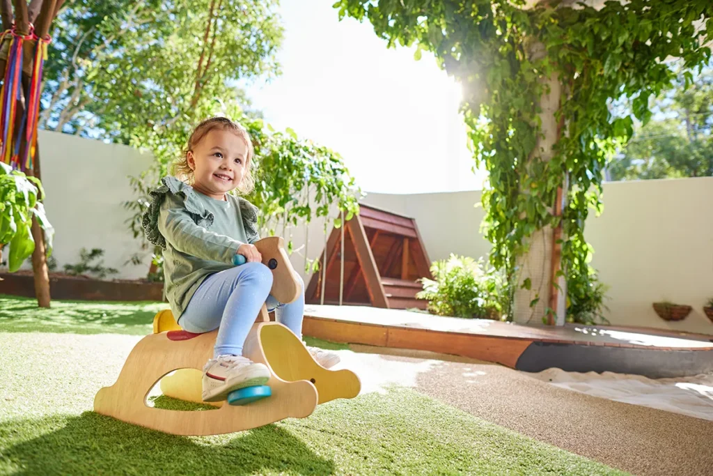 Toddler girl on rocking horse in outdoor playground