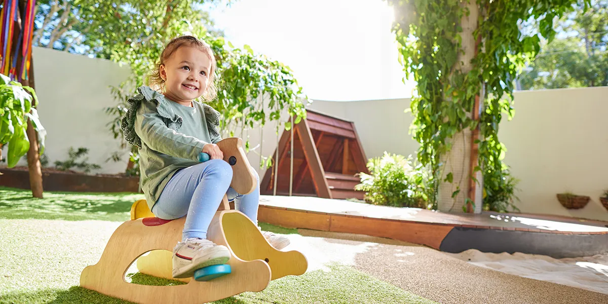 Toddler girl on rocking horse in outdoor playground