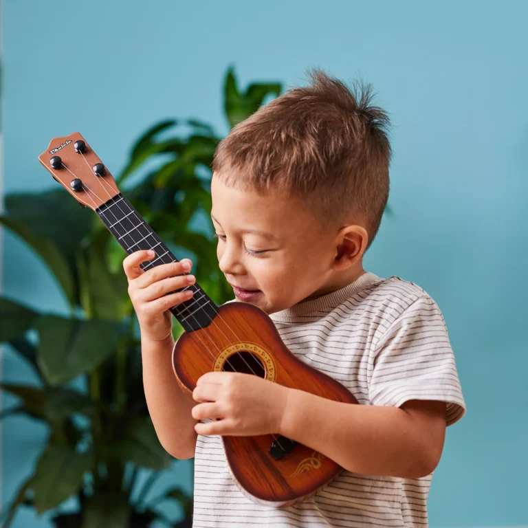 Kindergarten boy playing a ukulele at Amberton Beach day care