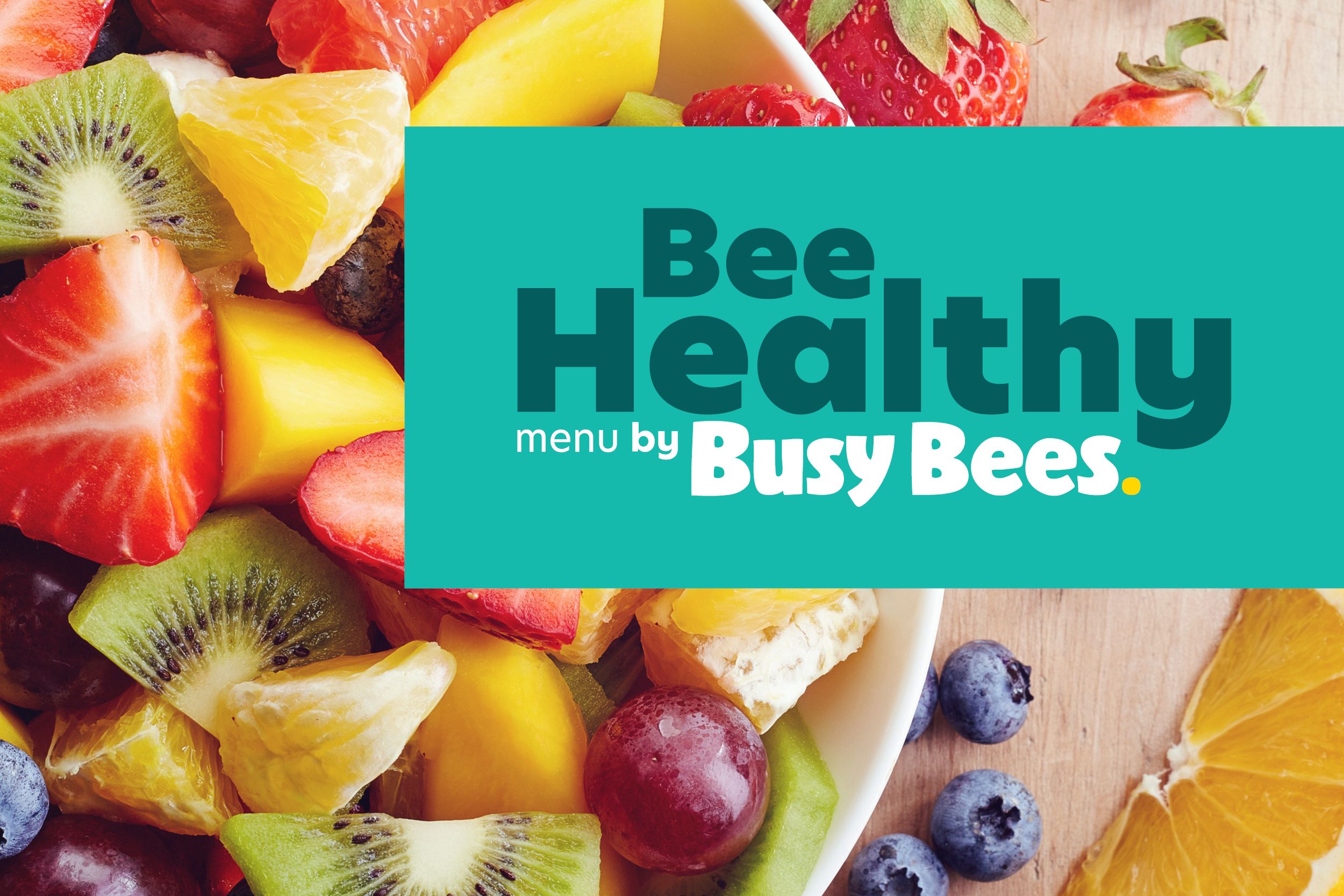 A bowl of fruit salad with an overly text saying "Bee Healthy menu by Busy Bees".